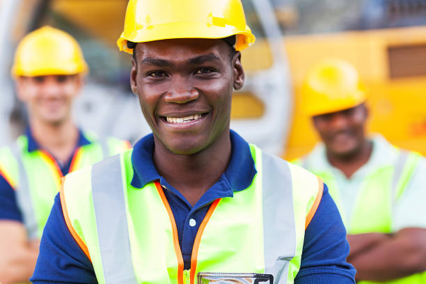 happy african american construction worker in front of colleagues