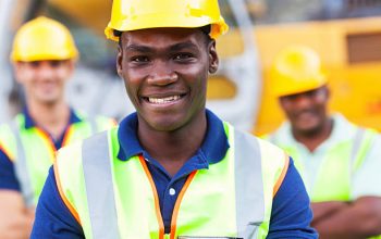happy african american construction worker in front of colleagues